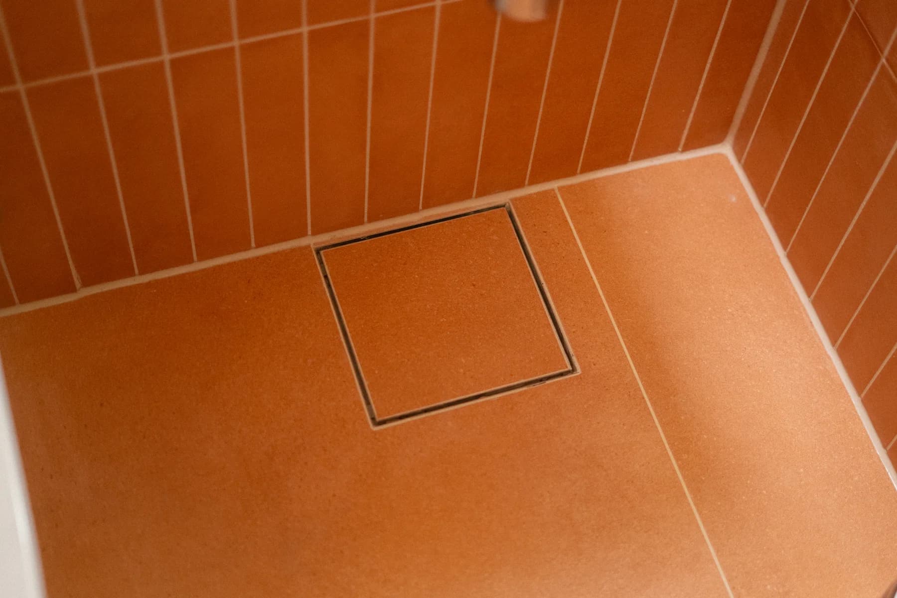 Terrakottafargede gulvfliser med tile insert-sluk hos Rosendal Bygg